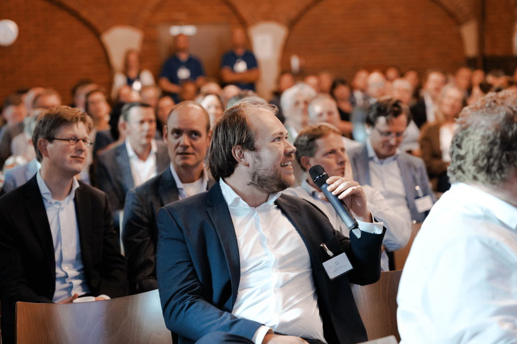 Deelnemer van Fizi Jaarevent stelt een vraag tijdens een plenaire sessie