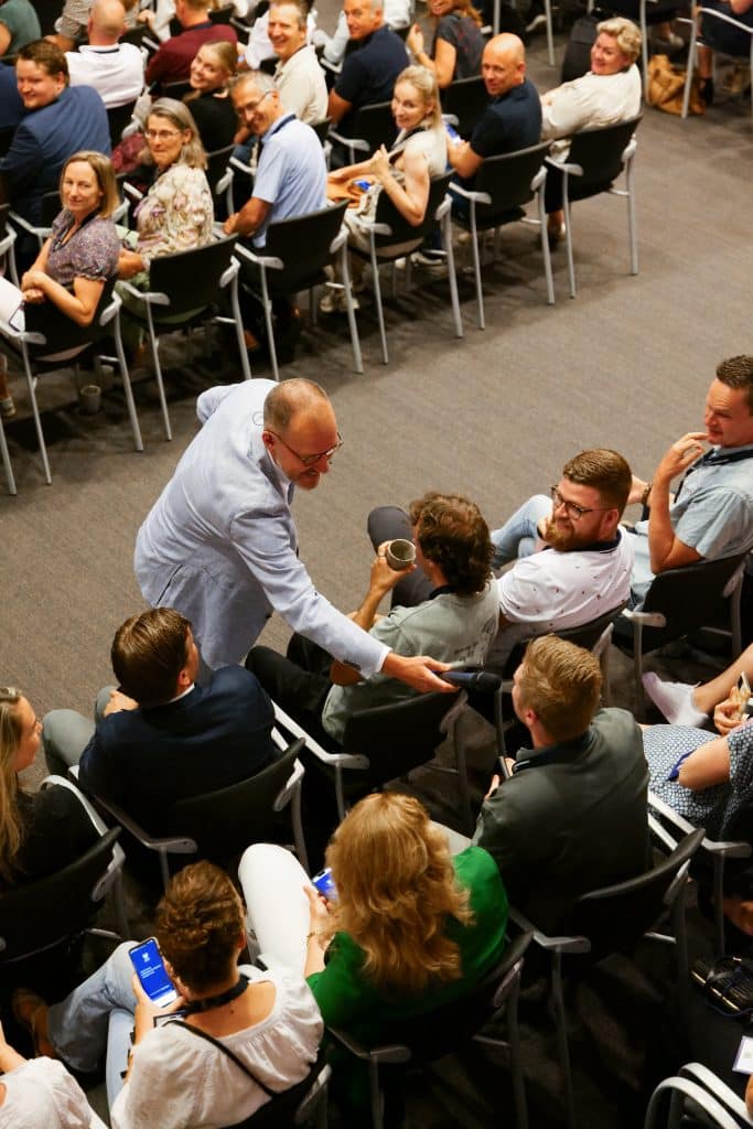 Dagvoorzitter Hans Oosterkamp stelt een vraag aan een deelnemer tijdens het Fizi Jaarevent 2025